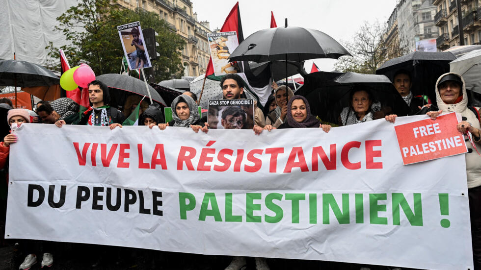 Protesters march behind a banner which reads as "Long live resistance of Palestinian people" as they take part in a demonstration to demand an "immediate ceasefire in Gaza". 