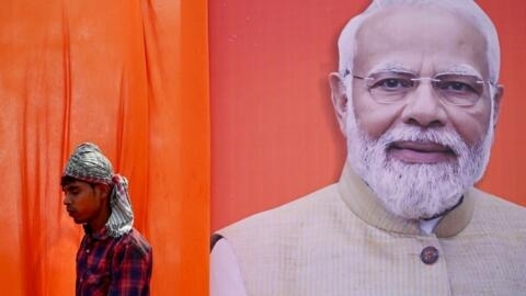Eleitor passa em frente de cartaz do primeiro-ministro Narendra Modi, que fará uma meditação na fase final das eleições gerais