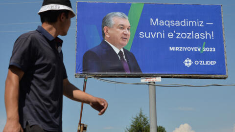 Мужчина на фоне предвыборного билборда действующего президента и кандидата в президенты Узбекистана Шавката Мирзиёева в Красногорске, примерно в 60 км от Ташкента, 8 июля 2023 года.