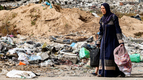 Une femme et un enfant arrivent à pied dans le quartier de Daraj, dans la ville de Gaza, le 11 mai 2024, au milieu du décombres.