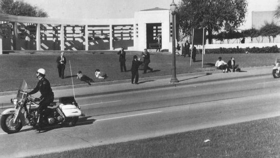Ein Foto kurz vor dem Attentat auf John F. Kennedy. Rechts am Straßenrand sitzend: der "Umbrella ...
