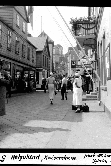 Schwarz-Weiß-Aufnahme: Menschen flanieren auf einer Einkaufsstraße.