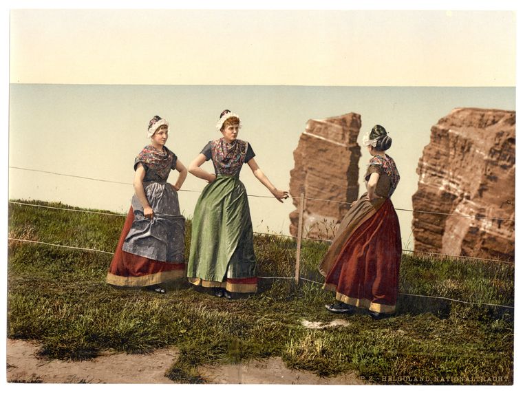 Drei Frauen in langer, bunter Tracht. 