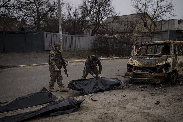 殺害された民間人の遺体を回収するウクライナ兵＝5日、ウクライナのキーウ郊外ブチャで(AP)