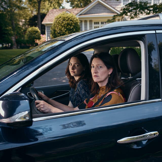 Kathleen Lomax sitting in the driver’s seat of a car, with her daughter Bridget in the passenger’s seat and her other daughter, Morgan, in the back seat.